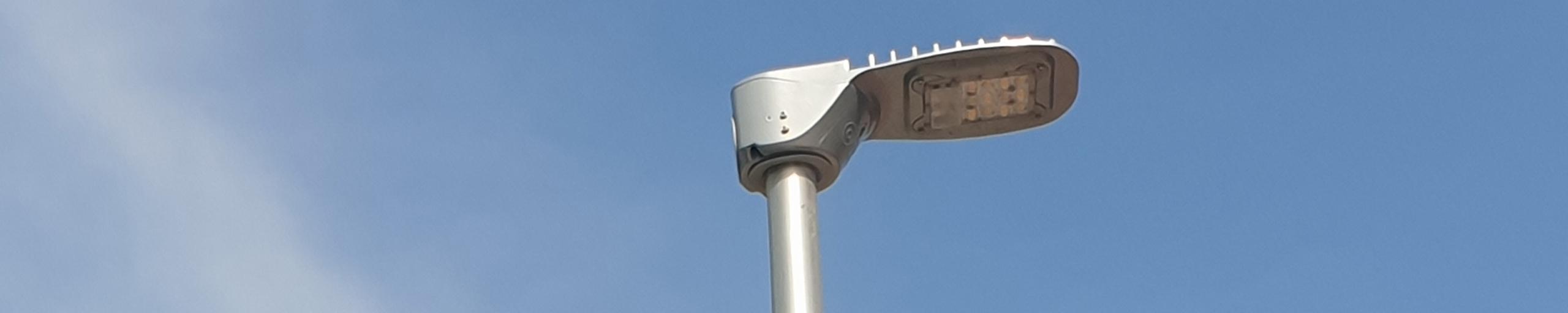 Lantaarnpaal gefotografeerd tegen een blauwe lucht met wolken